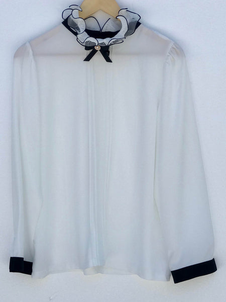 Elegant Ruffle Blouse with bow and pearl detail, shown in cream, features ruffled neckline and back closure, versatile formal wear.