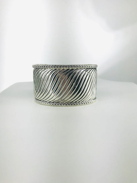 Silver-tone cuff bracelet with twisted wave design, intricate beaded edges, and open-back fit for comfort and elegance