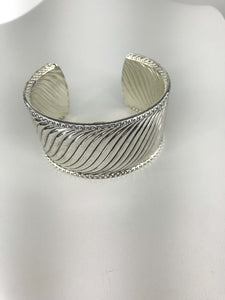 Silver-tone cuff bracelet with twisted wave design, intricate beaded edges, and open-back fit for comfort and elegance