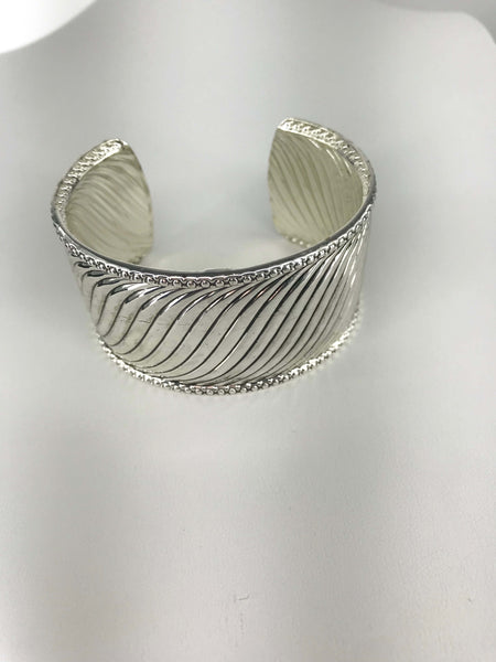 Silver-tone cuff bracelet with twisted wave design, intricate beaded edges, and open-back fit for comfort and elegance