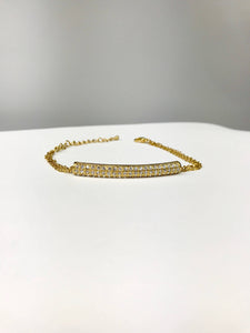 Gold-tone bracelet with curved bar centerpiece, cubic zirconia stones, double-chain, and adjustable clasp for elegant style.