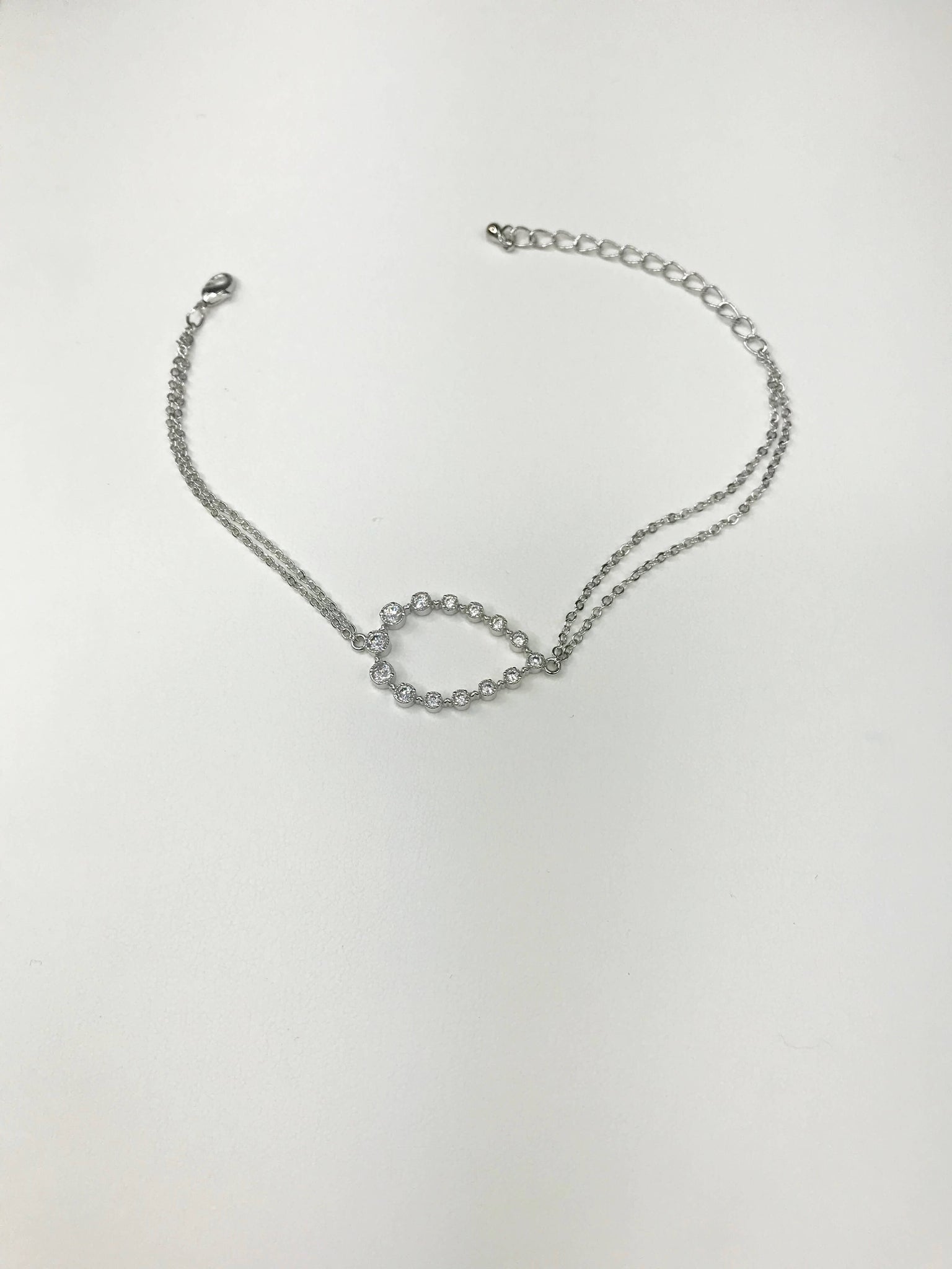 Silver-tone bracelet with double-chain, crystal-accented oval centerpiece, and adjustable lobster clasp for timeless elegance.