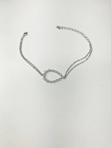 Silver-tone bracelet with double-chain, crystal-accented oval centerpiece, and adjustable lobster clasp for timeless elegance.