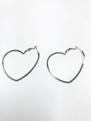Heart-Shaped Hoop Earrings crafted from polished stainless steel, featuring a chic heart silhouette with a secure latch-back closure, displayed elegantly to highlight their timeless and modern design. Also available in a radiant gold-tone finish.