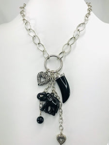 Scratch-resistant black and silver charm necklace with claw-shaped pendant, elephant charm, heart accents, and matching drop earrings.