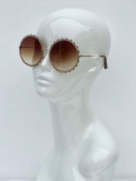 Scalloped round sunglasses with gradient lenses and intricate metal frames. Retro-inspired style with UV protection.