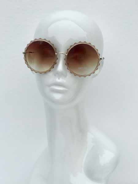 Scalloped round sunglasses with gradient lenses and intricate metal frames. Retro-inspired style with UV protection.