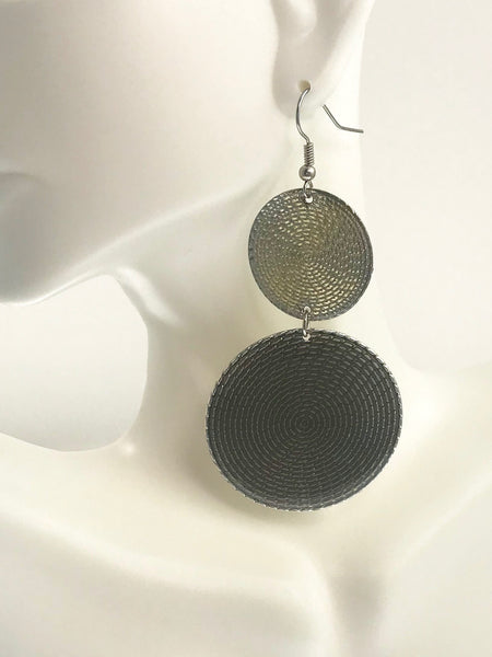 Bold double-disc dangle earrings with textured spiral patterns in gradient black and gold tones, displayed on a mannequin to showcase their 3-inch length and elegant cascading design. Lightweight, nickel-free, and perfect for any outfit.