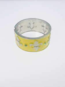 Yellow enamel cuff bracelet with silver-tone fleur-de-lis accents and green rhinestones.